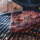 Barbecued brisket on a grill with a blurred background