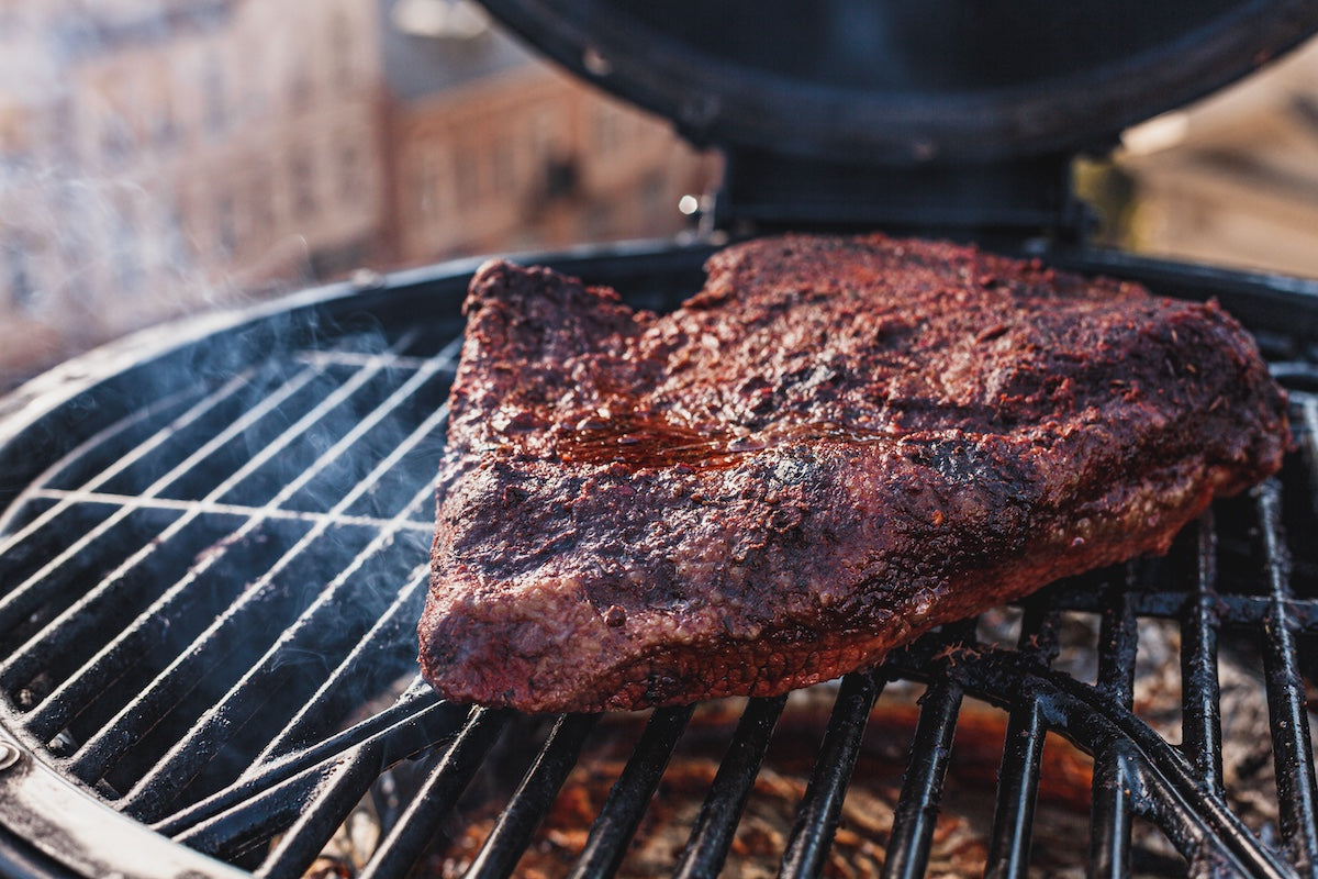 Barbecued brisket on a grill with a blurred background