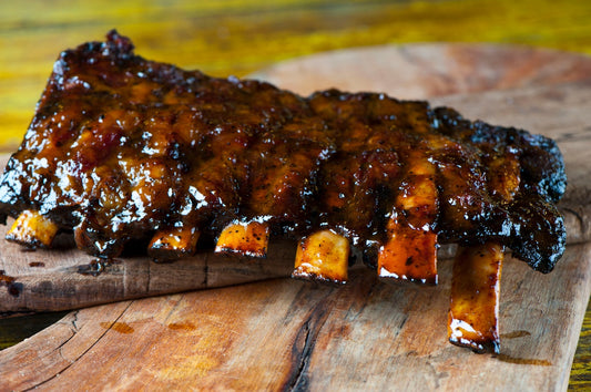 Braised ribs with a glossy sauce on a wooden cutting board